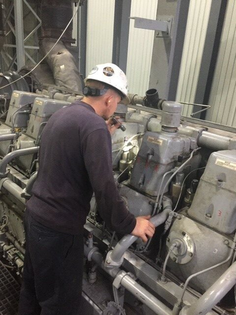 A man in hard hat working on an engine.