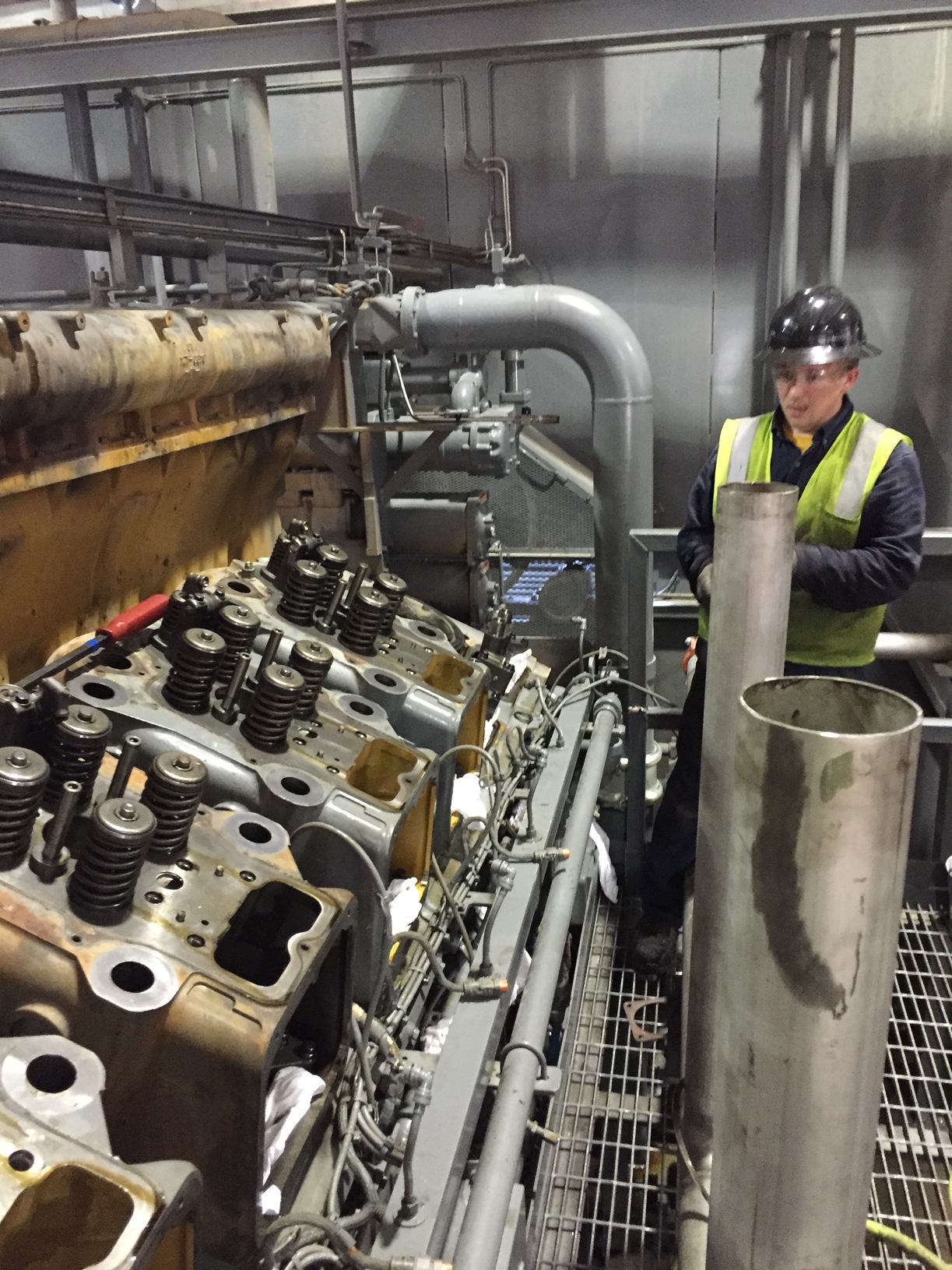 A man in safety gear standing next to an engine.